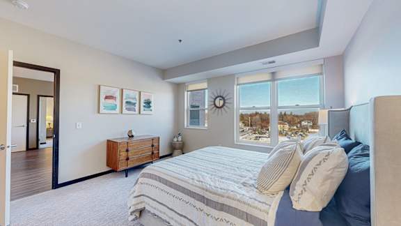 A bedroom with a large bed and a dresser with a mirror above it.