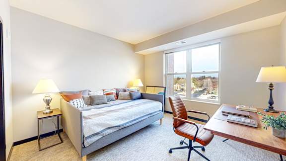 A bedroom with a bed, desk, and chair.