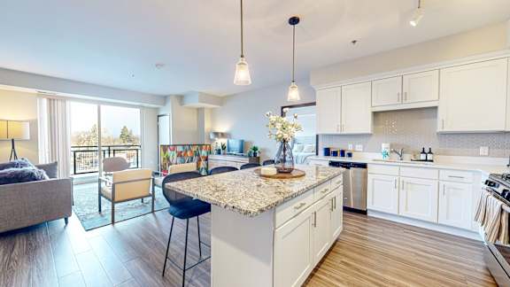 A modern kitchen with a large island and a living area with a couch and chairs.