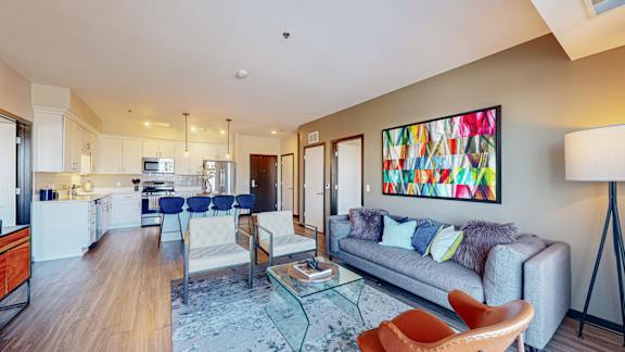 A modern living room with a grey couch and a painting on the wall.
