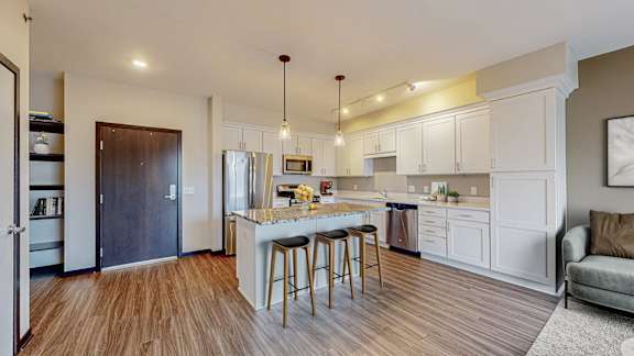 A kitchen with a white countertop and a bar stool.