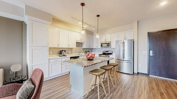 A kitchen with a white island and stools.