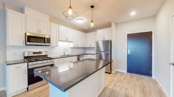 a kitchen with white cabinets and black countertops
