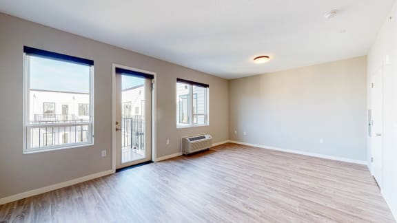 an empty living room with three windows and a door leading to a balcony