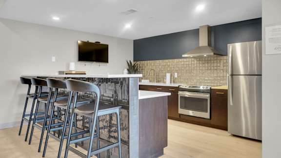 A modern kitchen with a bar area and stainless steel appliances.