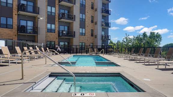 A swimming pool in front of a multi-story apartment building.