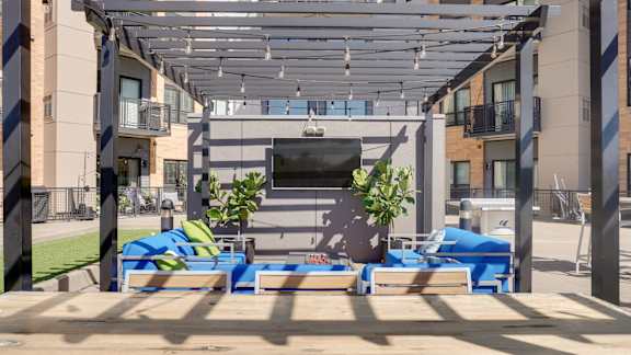 A modern outdoor seating area with blue cushioned benches and a wooden table.