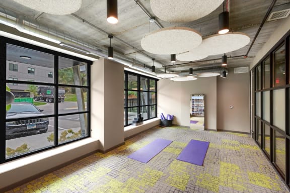 a yoga room with purple yoga mats on the floor and large windows
