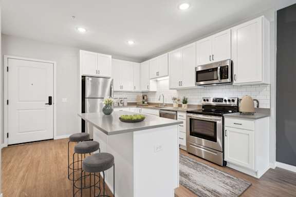 A kitchen with white cabinets and a large island.