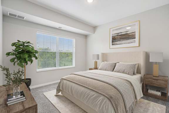 A well-lit bedroom with a large bed and a potted plant.