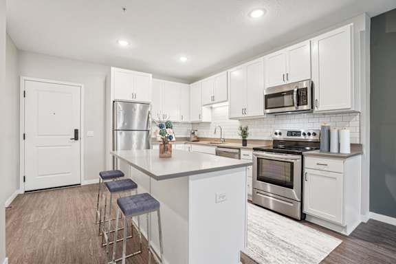 A kitchen with white cabinets and a white island.