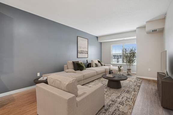 A living room with a grey wall and a white couch.