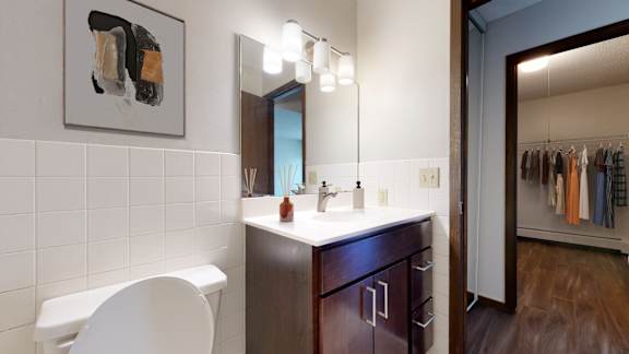 A bathroom with a white chair, a sink, and a mirror.