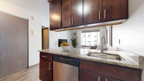 A kitchen with dark wood cabinets and a stainless steel dishwasher.