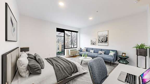 A modern bedroom with a large bed and a laptop on the desk.