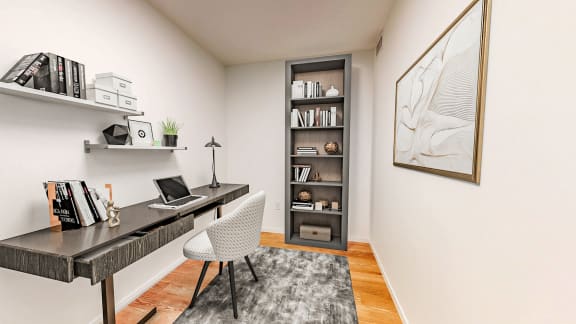 a home office with a desk with a laptop and a book shelf