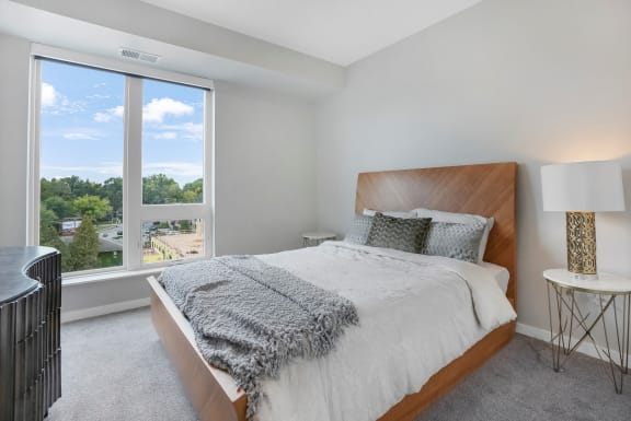a bedroom with a large window and a bed with a wooden headboard