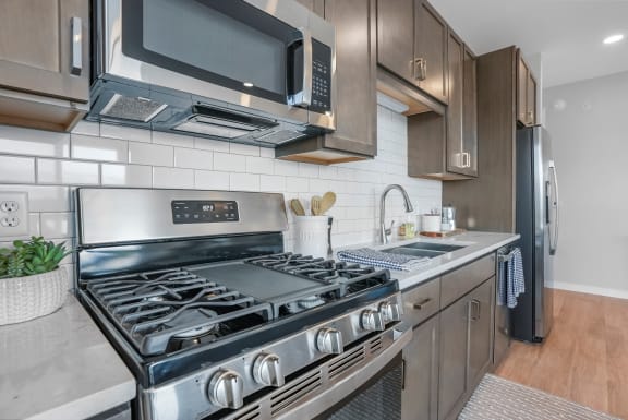 a kitchen with a stove top oven next to a sink and a microwave