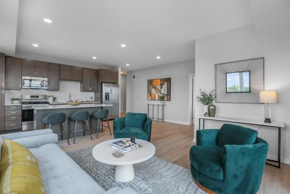 a living area with a couch coffee table and chairs and a kitchen with a breakfast bar