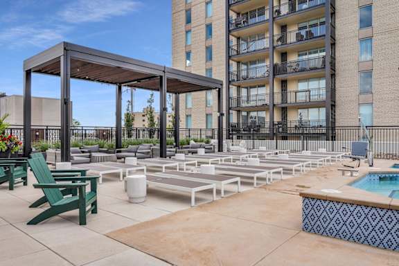 A pool area with a hot tub and lounging chairs.