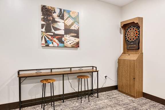 a table with stools and a clock in a room with a painting on the wall