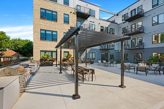 an outdoor patio with a grill and tables and chairs