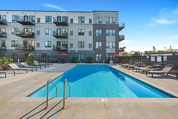 an apartment complex with a swimming pool and chaise lounge chairs