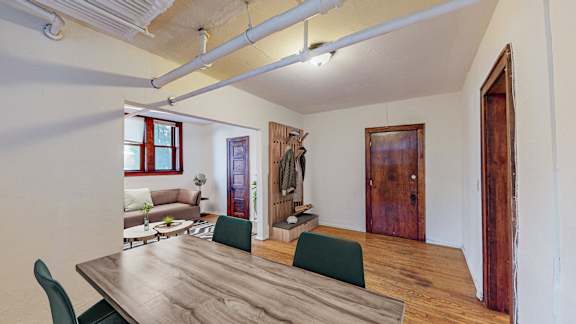 A room with a long wooden table and green chairs.
