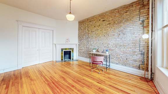 A room with a brick wall and wooden flooring.