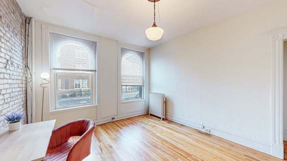 A room with a white brick wall and a wooden floor.