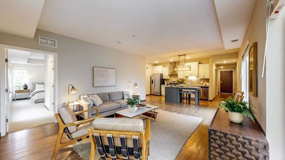 A well-lit, spacious living room with a grey sofa and a wooden coffee table.