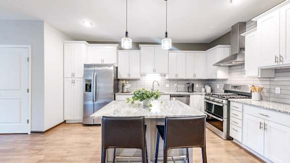 A kitchen with a table and chairs in the middle of it.