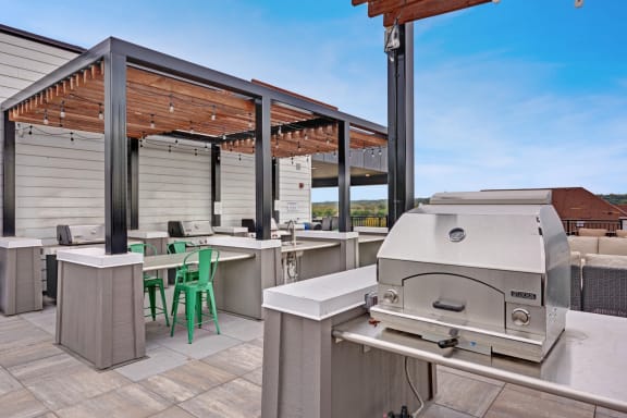 a barbecue grill on a patio with tables and chairs