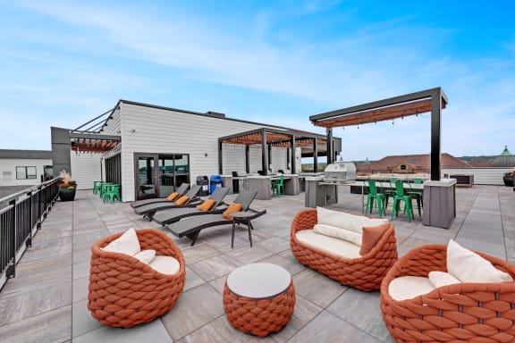a rooftop patio with chairs and tables and a building in the background