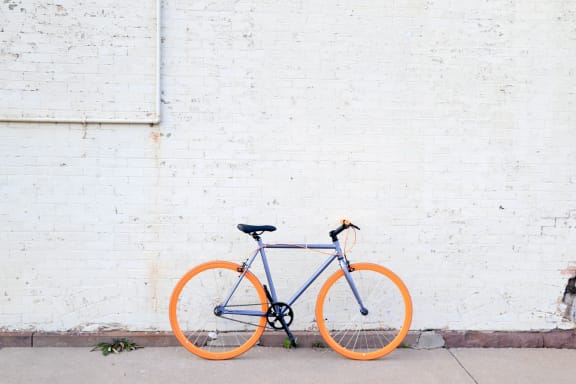 an orange and blue bike parked next to a white brick wall at Tyler Street Stacks, Minneapolis, MN 55413