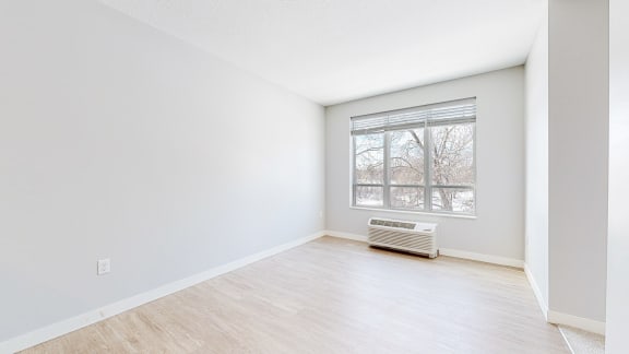 a bedroom with a large window and hardwood floors