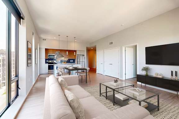 A modern living room with a long beige sofa and a glass coffee table.
