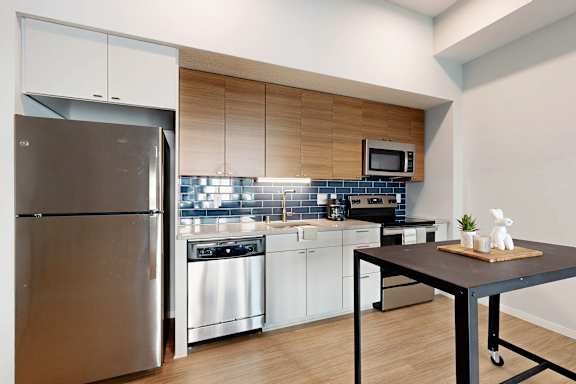 A modern kitchen with a stainless steel refrigerator and white cabinets.