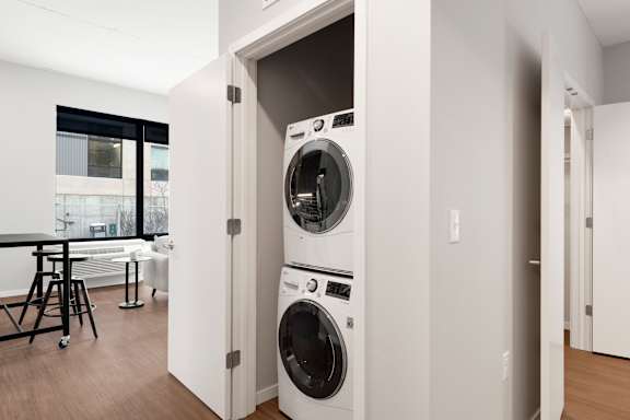 A white washing machine is built into a wall in a modern laundry room.at Viridium Apartments, Minneapolis