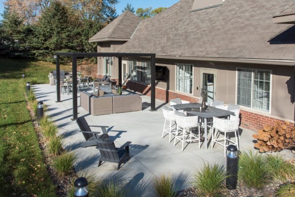 a patio with tables and chairs in front of a house
