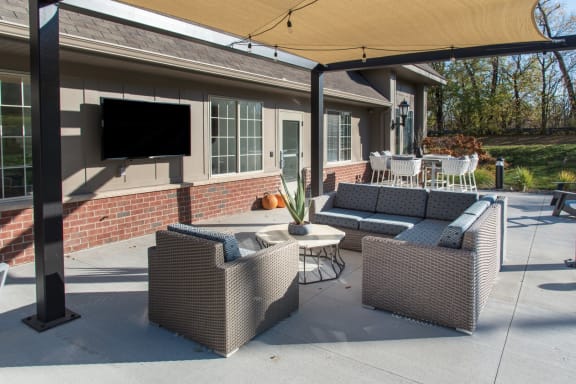 a patio with wicker furniture and a tv on the side of a house