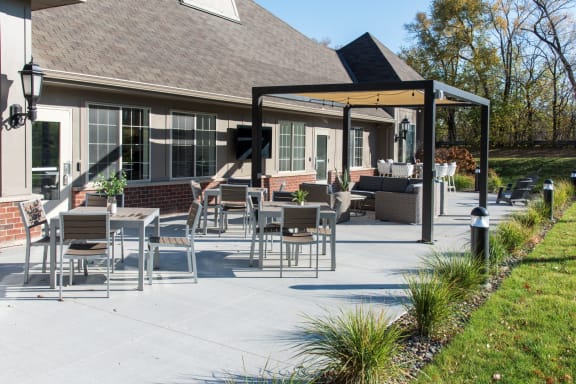a patio with tables and chairs in front of a house