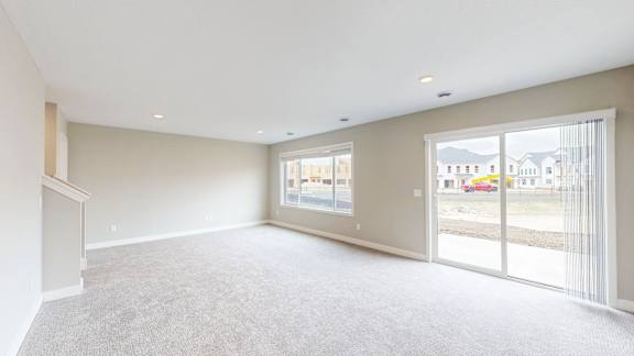 A spacious room with a carpeted floor and large windows.
