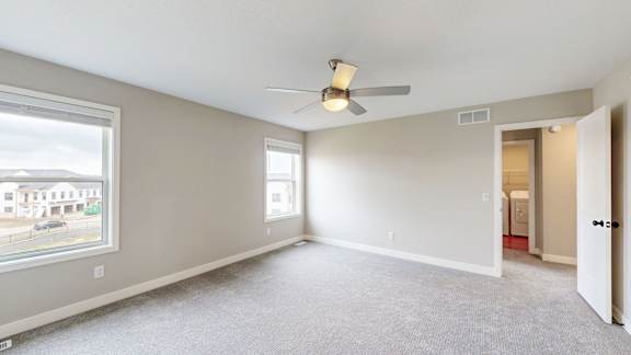 A spacious room with a ceiling fan and carpeted floor.