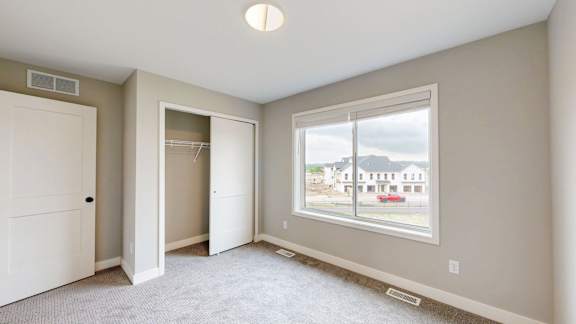 A room with a large window, a white door, and a white closet.