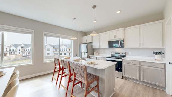 A kitchen with white cabinets and a large island with a sink.