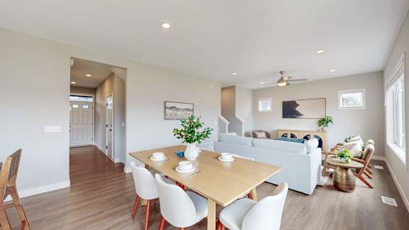 A dining room with a wooden table and white chairs.