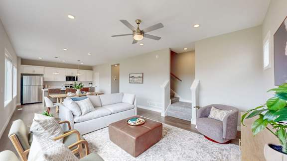A living room with a white couch, a brown coffee table, and a ceiling fan.