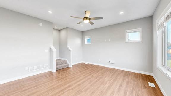 A room with a ceiling fan and wooden flooring.