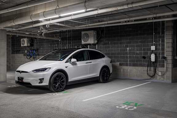 A white Tesla car is parked in a charging station.